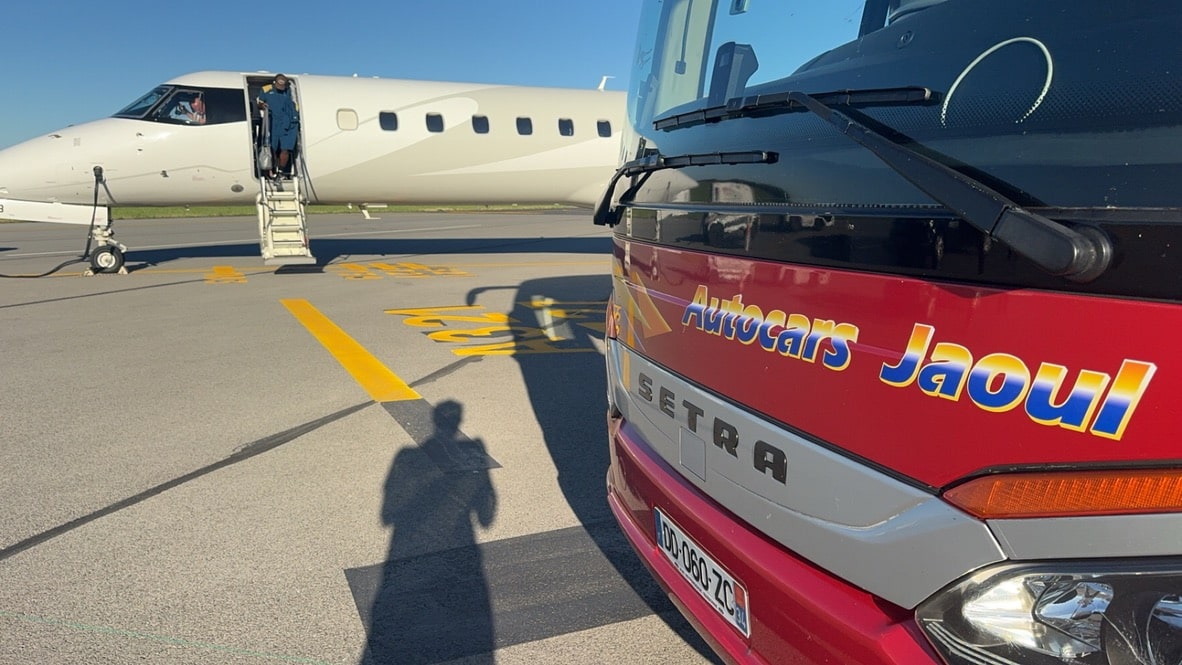 Autocar Jaoul Setra et avion sur tarmac, passager descendant les marches sous un ciel bleu.